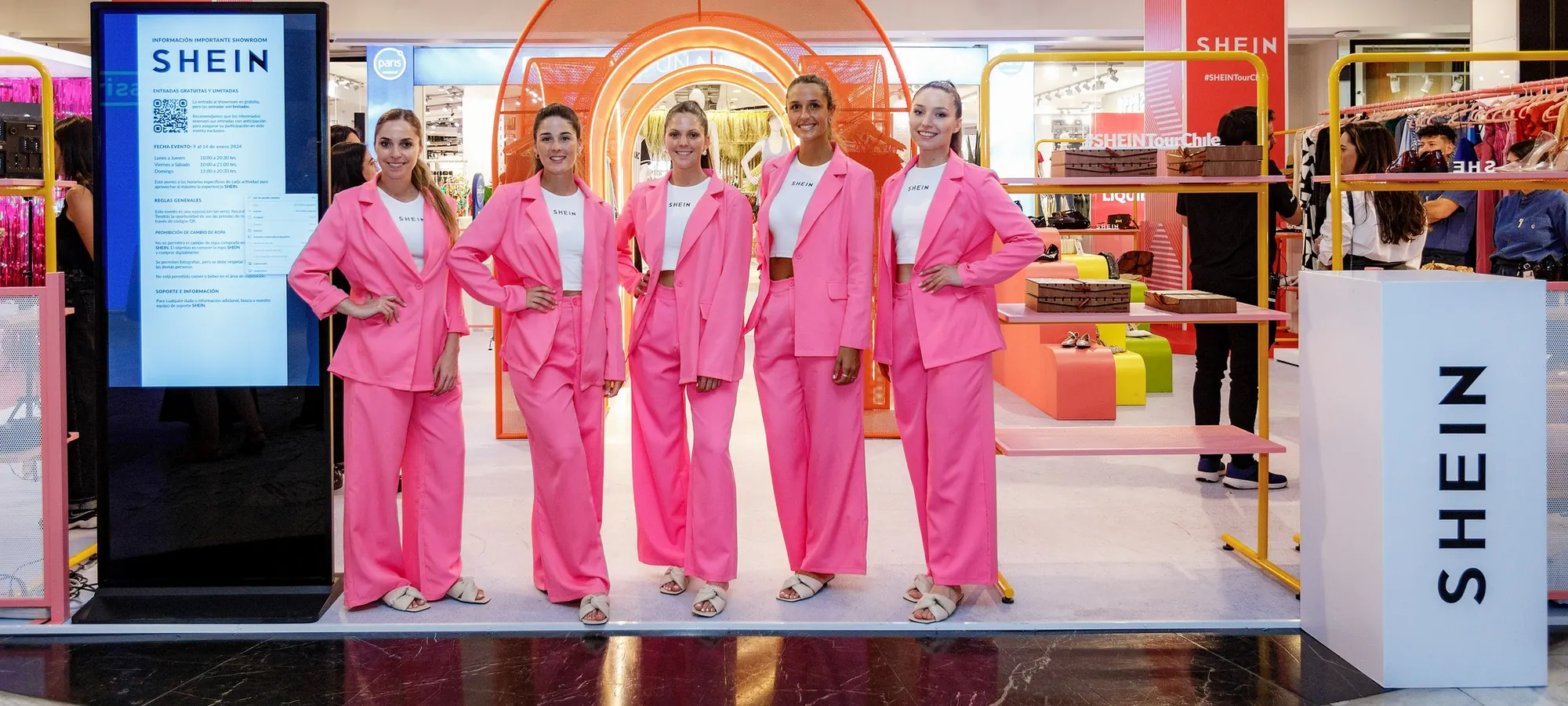 Cinco anfitrionas de pie en la apertura de una tienda de moda